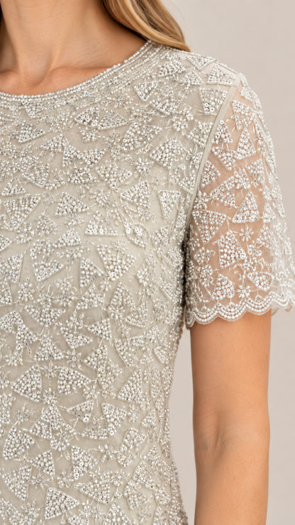 Close-up detail of intricate beading and scalloped sleeve hem on silver evening bodice