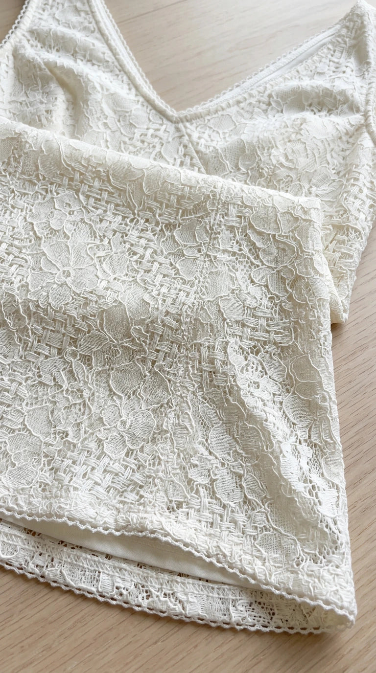Close-up detail of intricate ivory floral lace fabric and scalloped hem