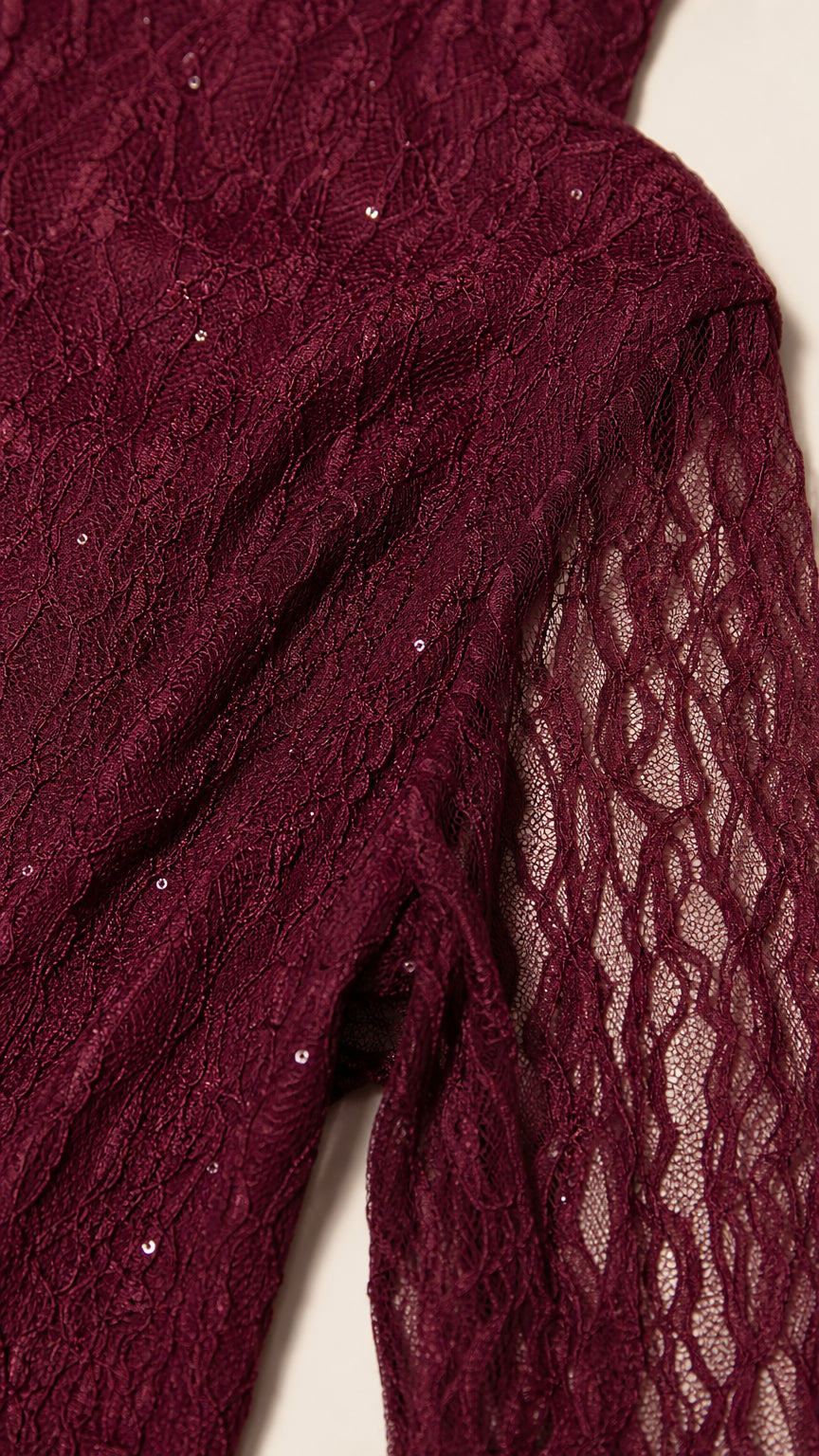 Close-up detail of burgundy sequin embroidered lace fabric and sheer sleeve