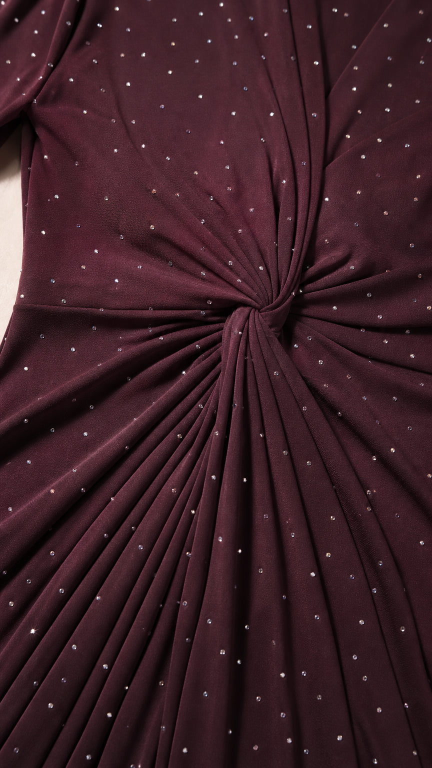 Close-up detail of twist knot waist and sparkling rhinestone embellishments on dark fabric