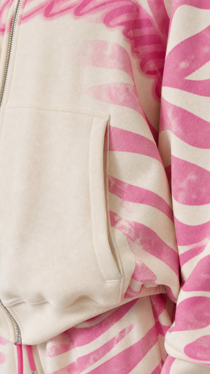 Close-up detail of pocket, metal zipper, and printed fabric on cream pink hoodie
