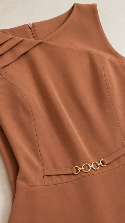 Close-up of asymmetrical pleated neckline and gold-tone waist chain accent on caramel brown dress