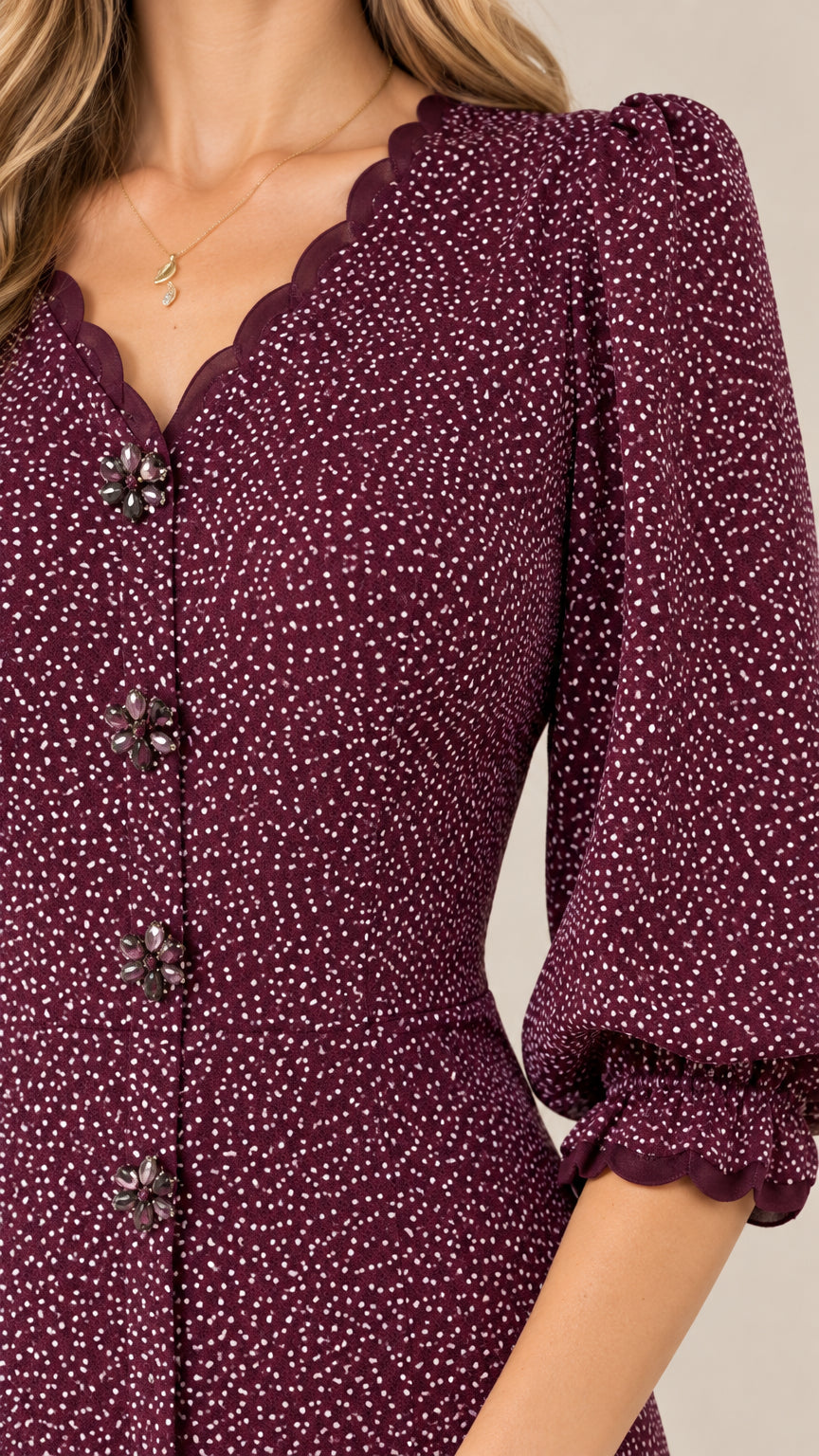 Close-up detail of scalloped V-neckline, ornamental buttons, and micro-dot pattern