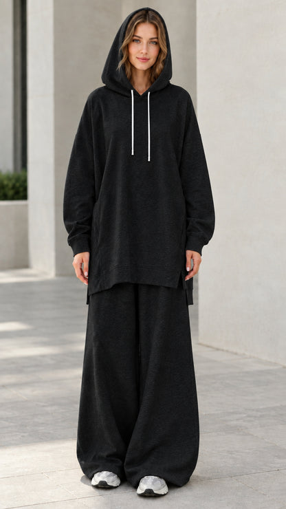 Woman wearing black oversized longline hoodie and matching wide-leg sweatpants lounge set