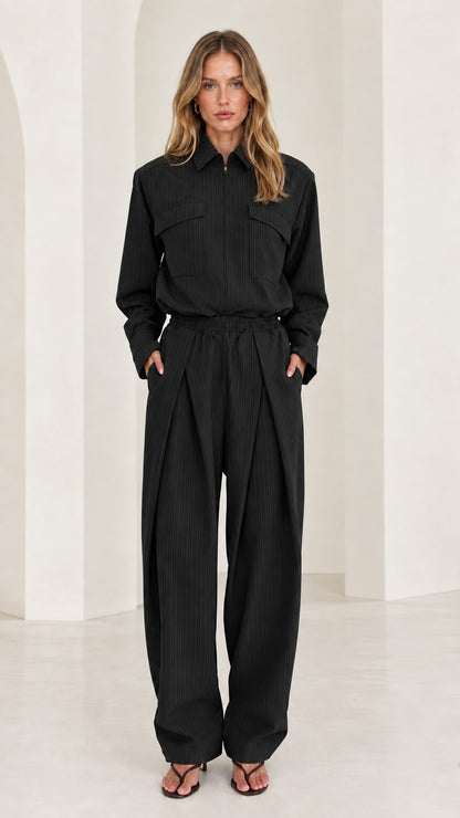 Front view of model wearing black long sleeve pleated wide-leg jumpsuit