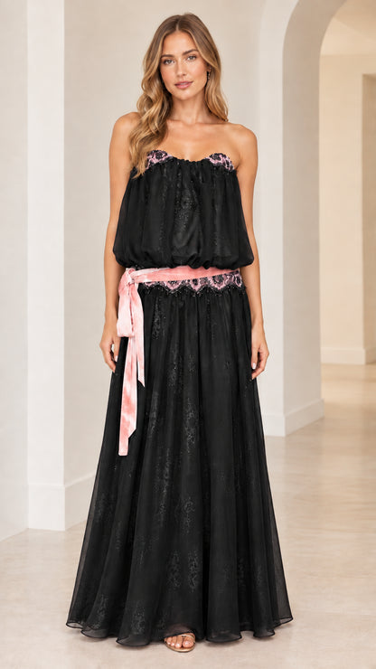 Front view of woman wearing strapless black blouson maxi dress with pink sash