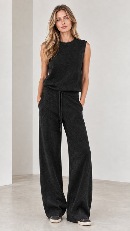 Full-body view of woman wearing Black sleeveless top and wide-leg knit pants set