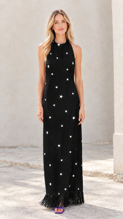 Woman wearing black star print halter maxi dress with fringe hem