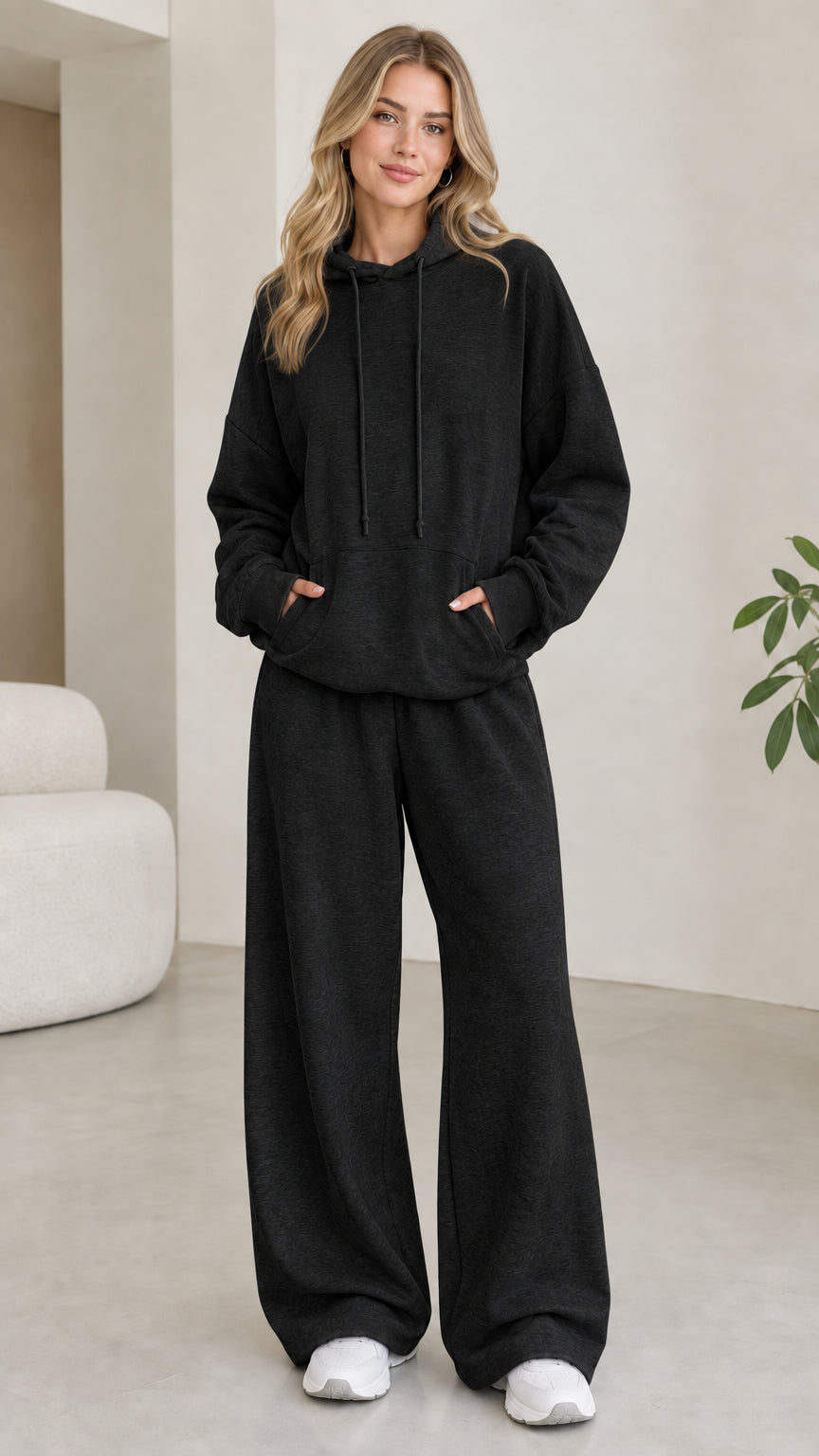 Model wearing black 2-piece drawstring hoodie and wide leg sweatpants set