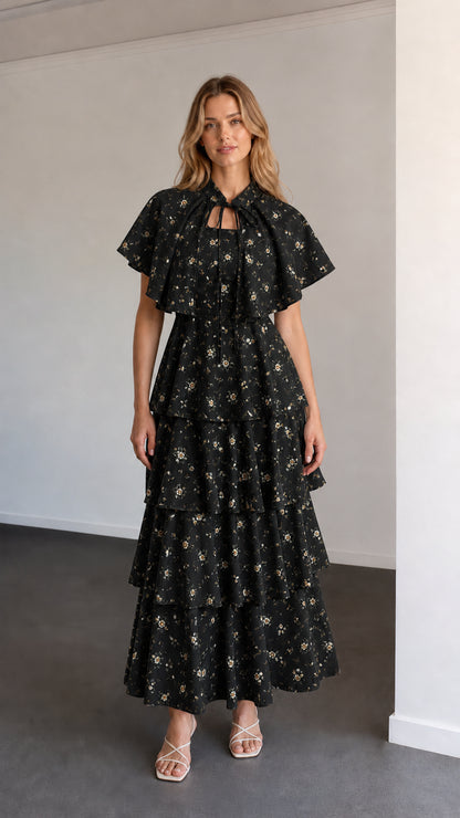 Full-length view of black floral capelet tiered maxi dress
