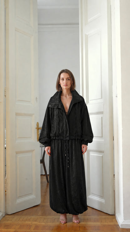 Front view of model wearing classic black zip-up jacket and balloon trousers set