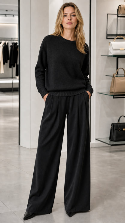 Model wearing black crewneck knit sweater with matching black wide-leg trousers