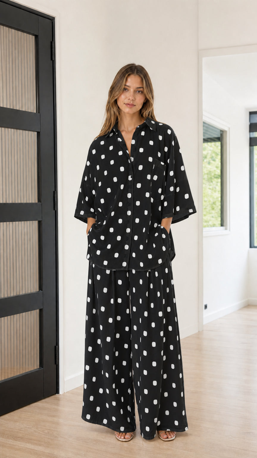 Front view of model wearing black and white polka dot button-down shirt and wide-leg pants set