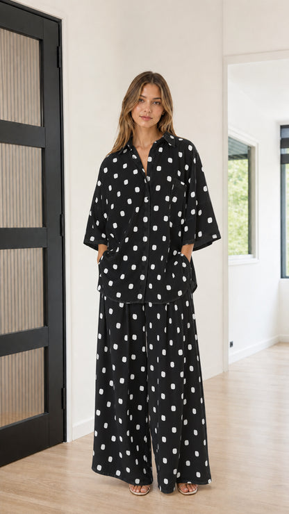 Front view of model wearing black and white polka dot button-down shirt and wide-leg pants set