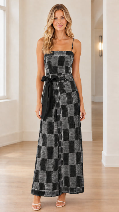 Front view of woman wearing black and grey checkered wide-leg jumpsuit with black waist belt