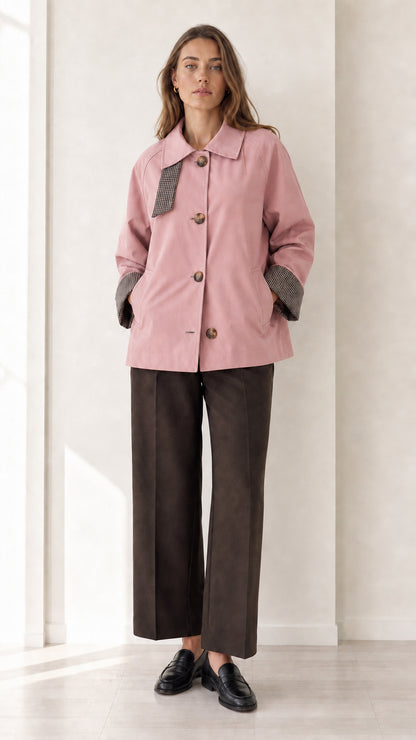 Front view of women's dusty pink short trench coat with check trim details