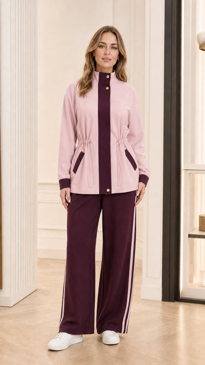 Model wearing light pink tracksuit jacket with burgundy trim and burgundy wide-leg pants