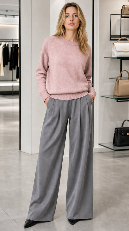 Model wearing dusty pink crewneck knit sweater with grey wide-leg trousers