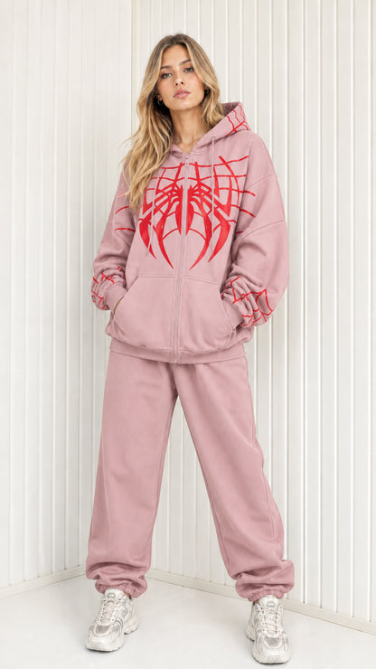 Front view of model wearing dusty pink graphic spider web zip hoodie and sweatpants set