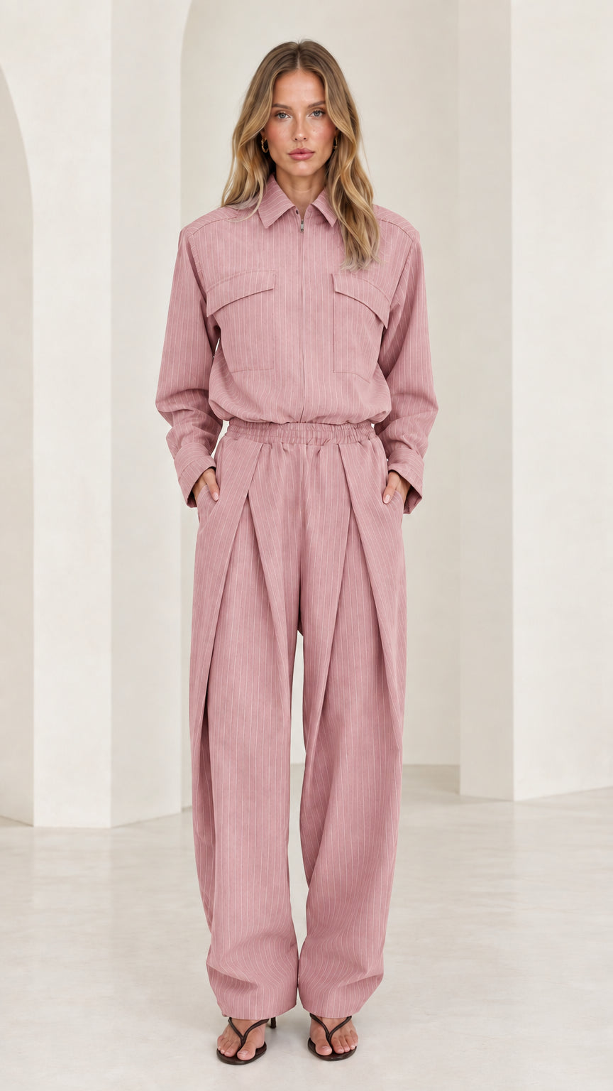 Front view of model wearing dusty pink long sleeve pleated wide-leg jumpsuit