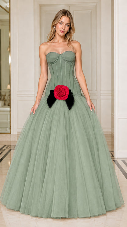 Model wearing sage green strapless corset tulle gown with red flower accent