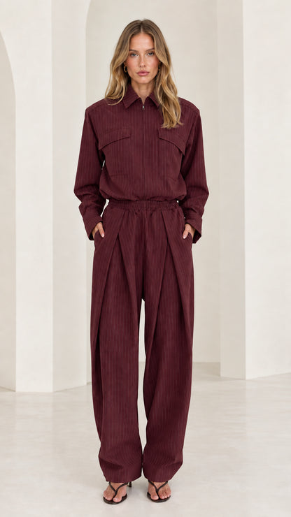 Front view of model wearing burgundy long sleeve pleated wide-leg jumpsuit