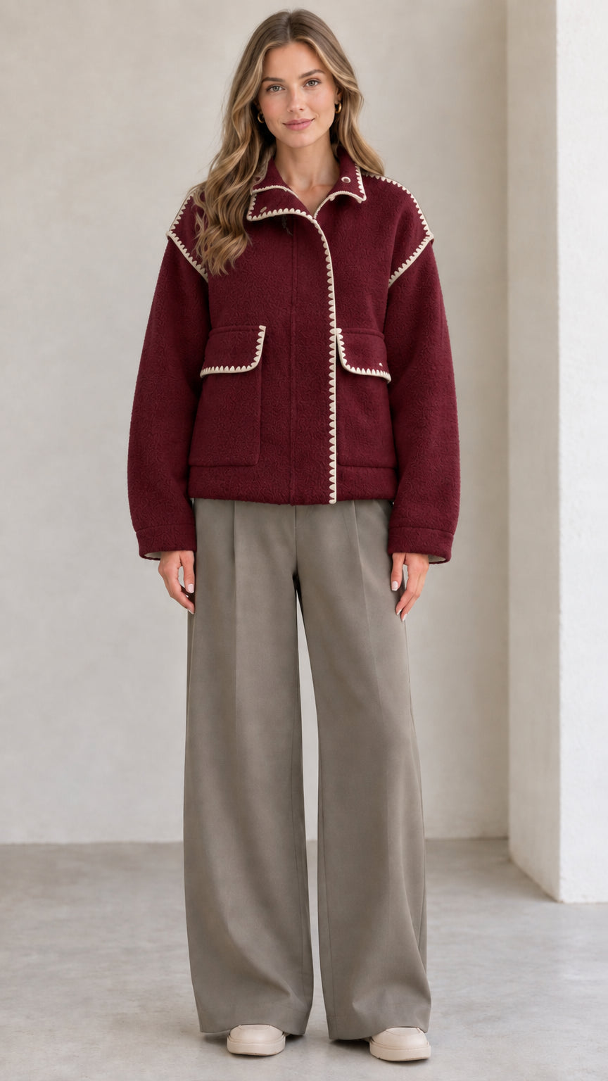 Model wearing burgundy red fleece jacket with white contrast blanket stitching