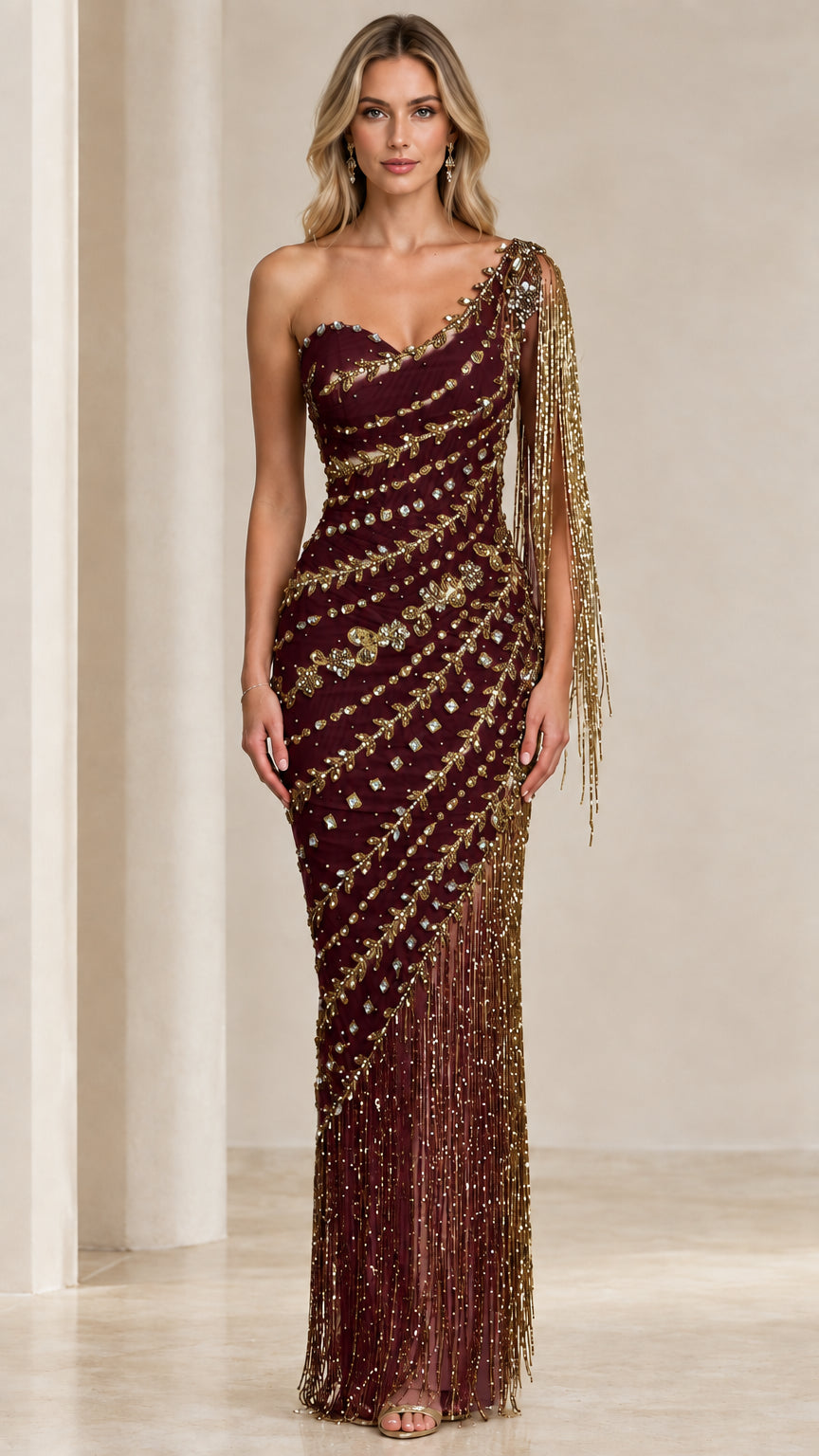 Front view of model wearing Burgundy and gold one-shoulder beaded fringe evening gown