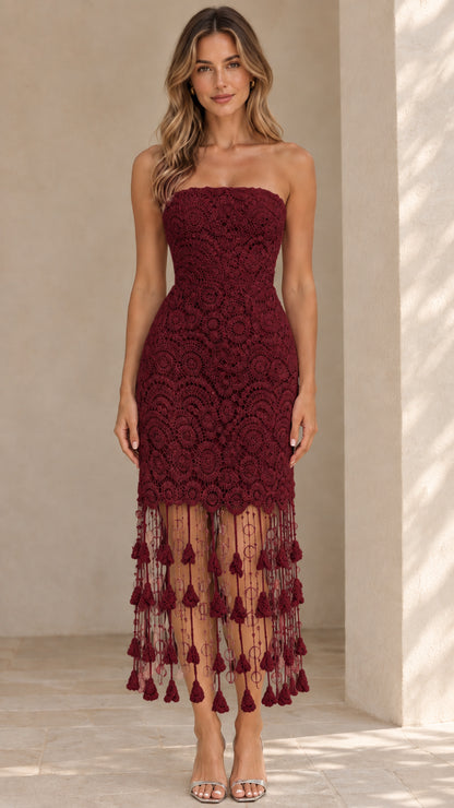 Front view of model wearing burgundy strapless lace midi dress with tassel hem