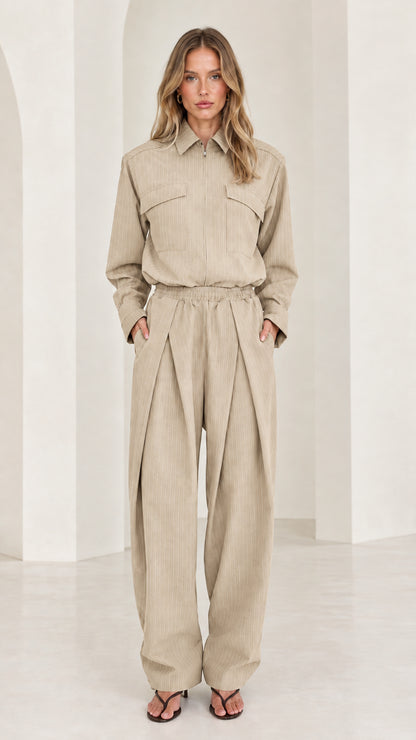 Front view of model wearing beige long sleeve pleated wide-leg jumpsuit